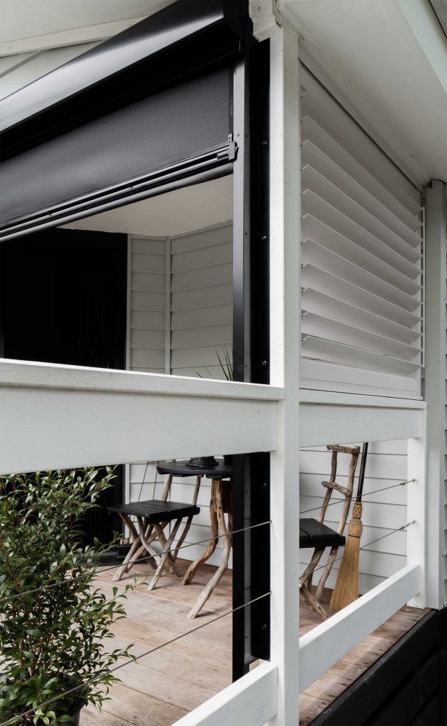 Side detail of a motorized zip-track screen housing and side rail on a covered porch