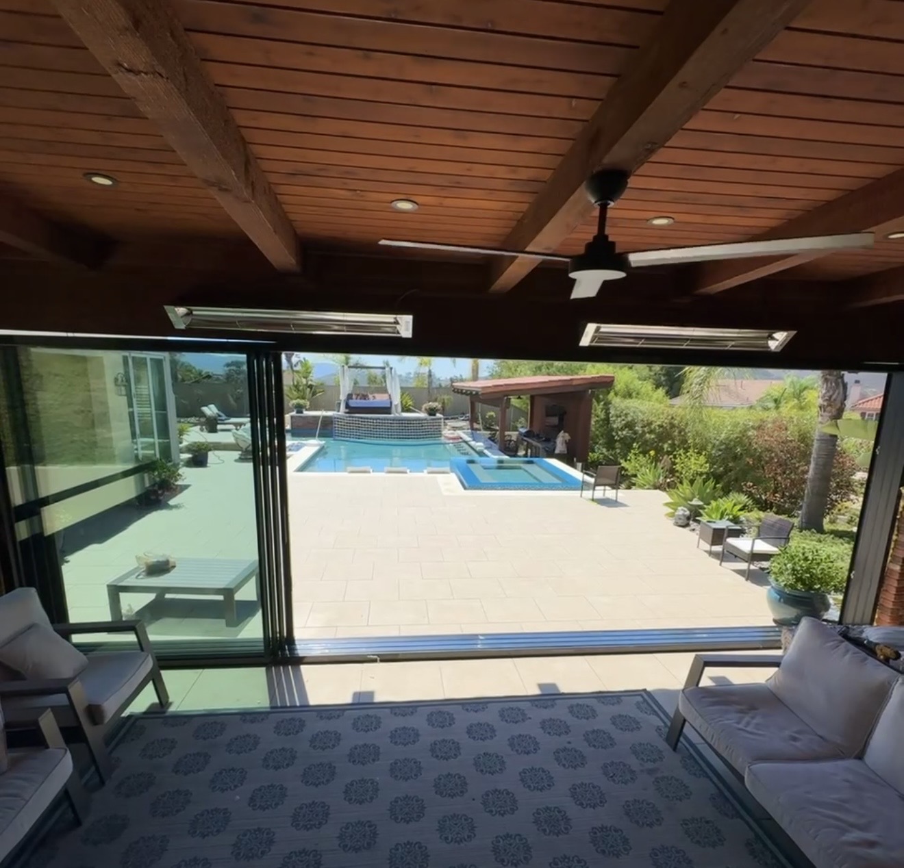 24-foot aluminum sliding glass wall open from a pool house living space to the pool patio