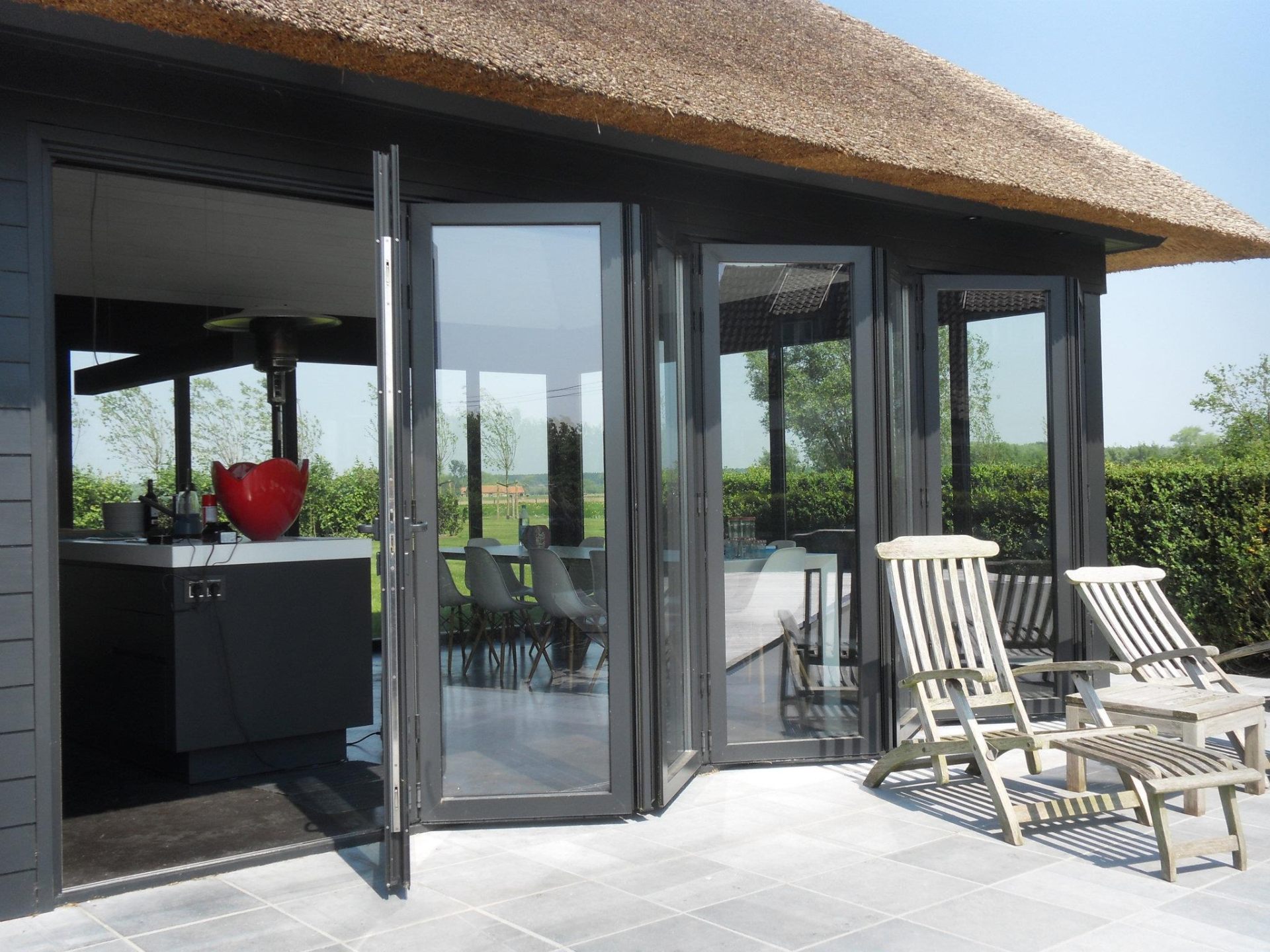 Aluminum bifold doors on thatched cottage — outdoor living