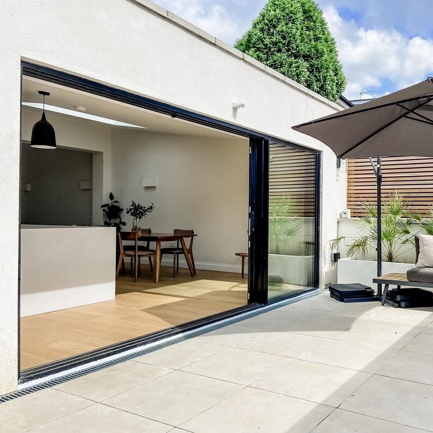 Bifold sliding door opening to modern patio with outdoor dining