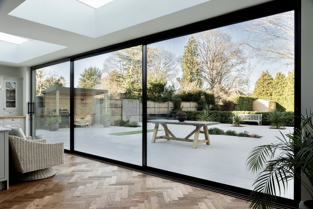 Large 3-panel sliding door with herringbone wood floors and garden view